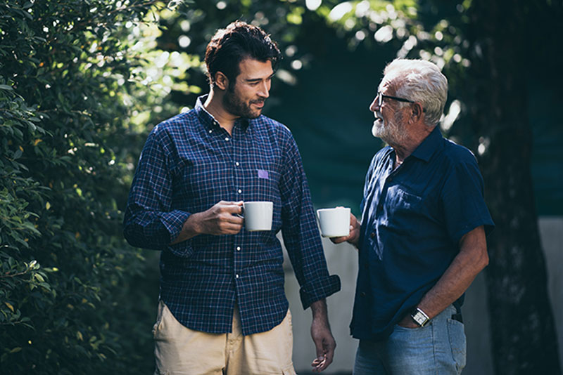 adult-son-and-senior-father-outside-drinking-coffee