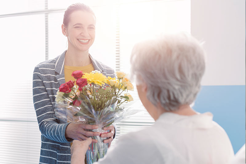 caregiver-handing-flowers-to-senior-lady